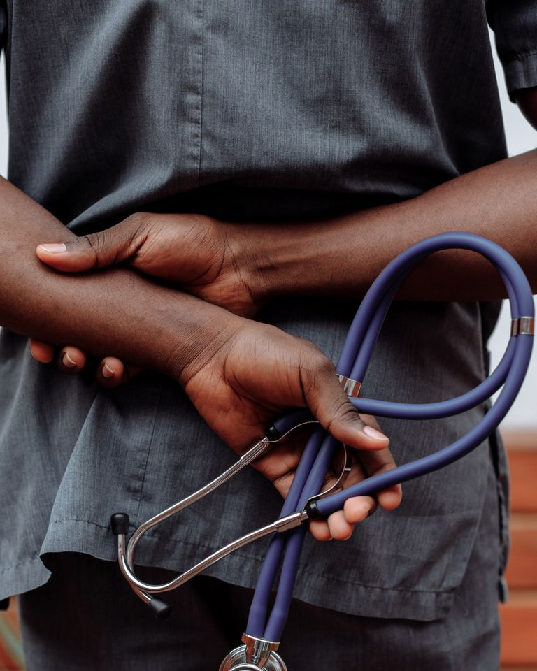 A clinician holds a stethoscope behind their back
